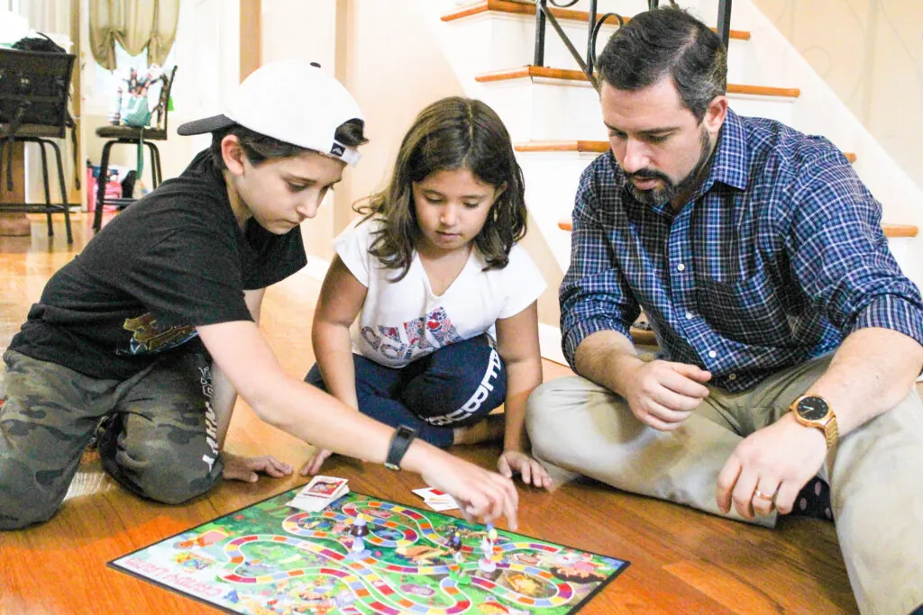 A team member playing a board game with two children