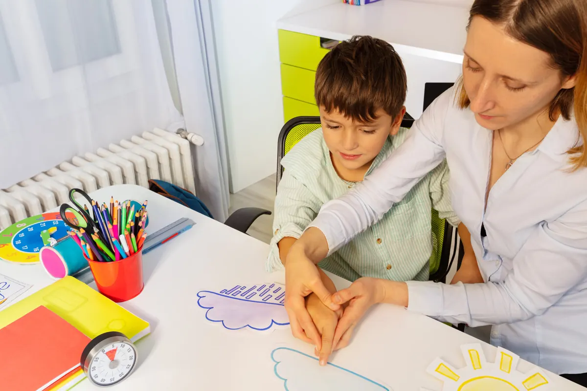 A tutor sitting with a boy at his desk