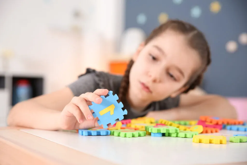 A young girl playing with colorful puzzle pieces