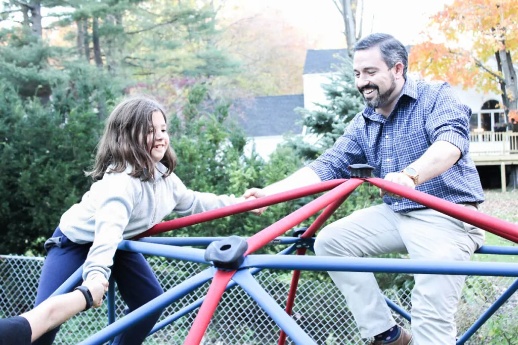 A team member and a young girl on a playground climbing dome