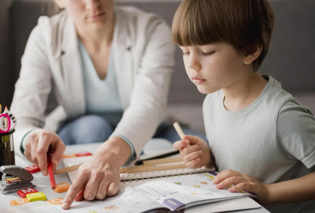 A teacher helping a boy with a worksheet